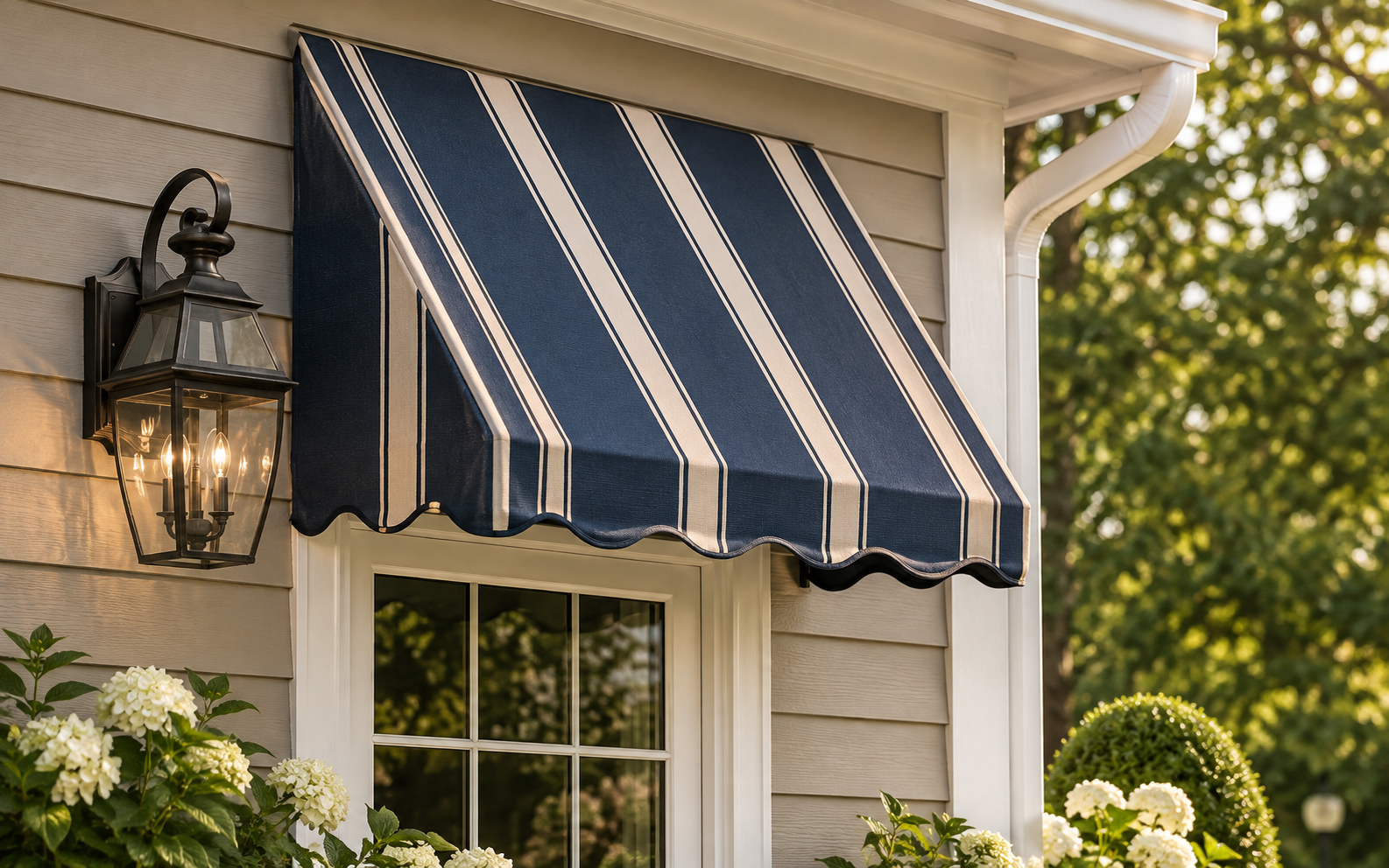 Navy and cream striped scalloped window awning above a double-hung window with hydrangeas below